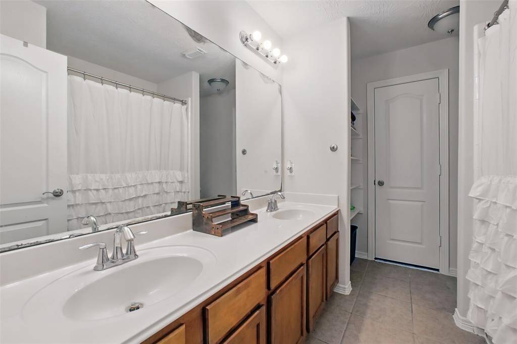 This secondary full bath has double sinks and lots of storage. Tub/shower combo.