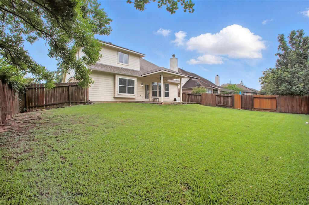 Spacious backyard with lush green lawn, mature trees, and full privacy fencing. The covered patio offers a perfect spot for relaxing or entertaining outdoors. Plenty of room to play, garden, or add future amenities—this backyard is a blank canvas for your lifestyle.