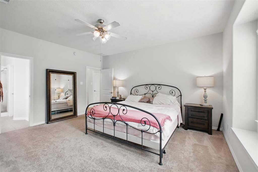 Alternate view of the spacious primary bedroom showcasing plush carpeting, neutral walls, and a large window that brings in abundant natural light. The room easily accommodates a king-sized bed and full bedroom suite, offering both comfort and style.