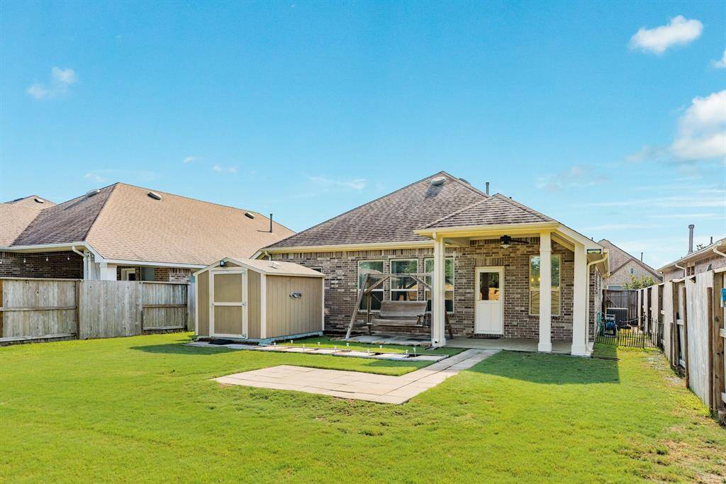 this view of the back shows the storage unit the pavers for grilling and the covered patio with swing to the side