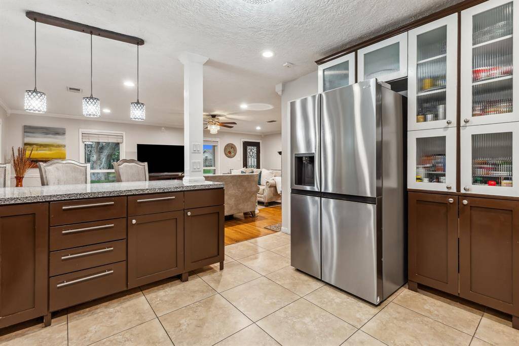 The extended granite peninsula offers ample prep space and bar seating for casual meals or entertaining guests. Stylish pendant lights and open views to the living room make this kitchen both functional and inviting.