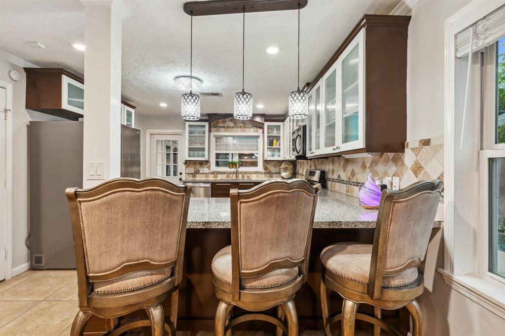 This thoughtfully designed kitchen features custom two-tone cabinetry, granite countertops, and a stainless steel gas range. Glass-front upper cabinets add a designer touch while providing great visibility and storage.