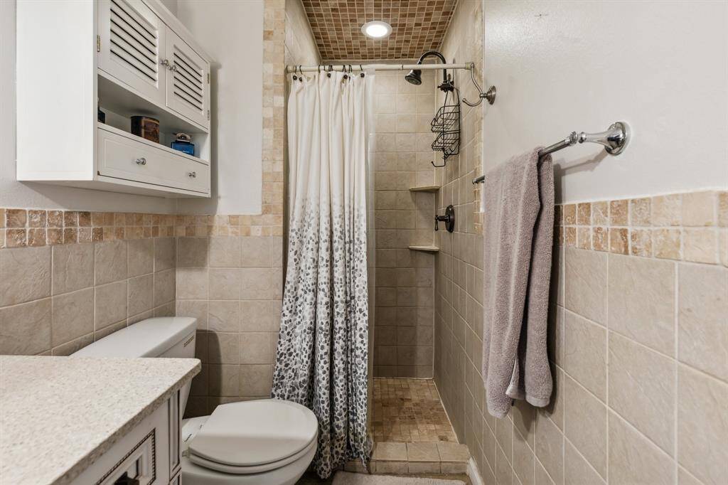 A walk-in tiled shower with thoughtful storage niches adds practicality and charm to this well-appointed private bath.