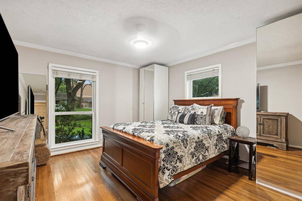 This secondary bedroom features two updated windows that invite in natural light and views of the surrounding greenery. With hardwood floors and a neutral palette, it’s ready to suit a variety of uses—from a stylish retreat to a creative space.