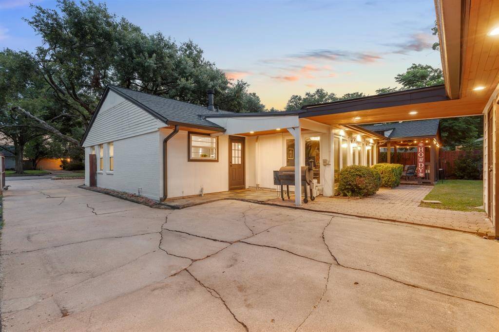 A standout feature of the home, the detached garage showcases a richly stained wood-style door and updated Wi-Fi-enabled opener for modern convenience. The breezeway is finished with a slate tile patio and tongue-and-groove ceiling detail, tying the front and backyard spaces together seamlessly.