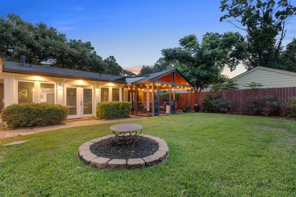 Spacious backyard with lush lawn offering ample room for outdoor fun. French doors lead to the bonus flex room, while the custom gable-covered patio creates a seamless indoor-outdoor connection.