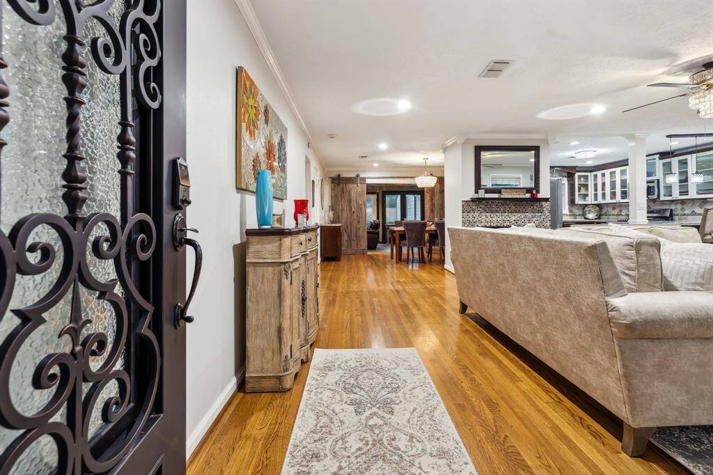 The spacious living room is anchored by a mosaic-tiled gas fireplace and surrounded by energy-efficient Simonton windows that fill the space with natural light. Recessed lighting, updated ceiling fans, and rich hardwood floors add both style and function.