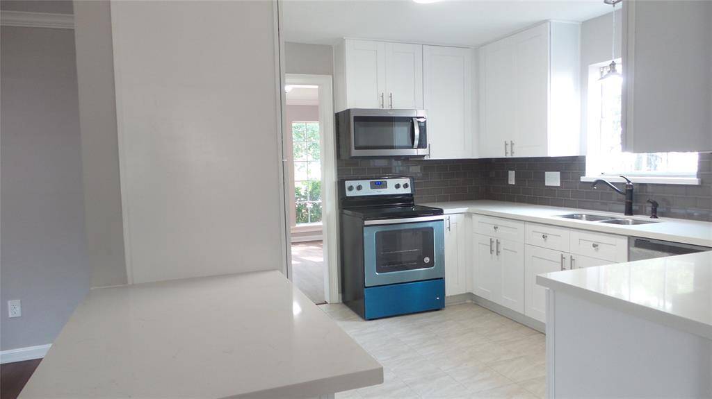 Updated kitchen with solid surface countertops, subway tile backsplash & stainless steel appliances.