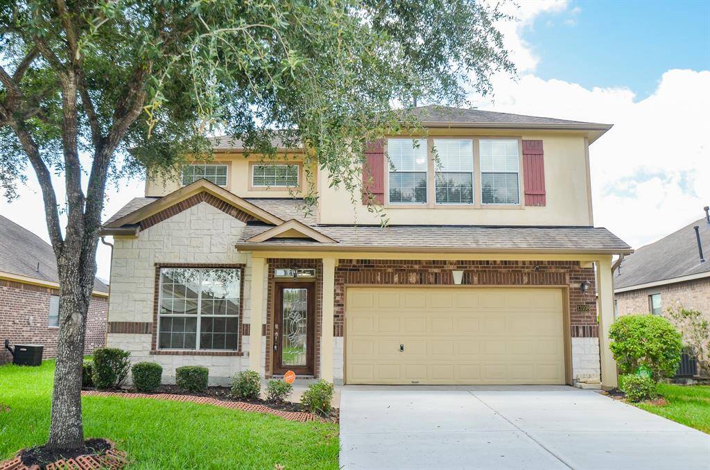 Charming two-story home with a mix of brick and stone exterior, featuring a double garage and well-maintained front lawn. Large windows provide ample natural light, and mature trees offer shade and privacy.