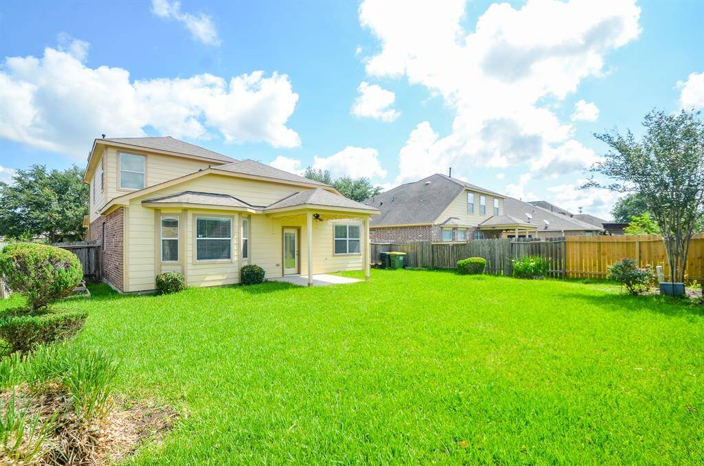 This photo shows a spacious backyard with lush green grass and a well-maintained two-story house featuring light-colored siding and multiple windows, offering a bright and inviting outdoor space.