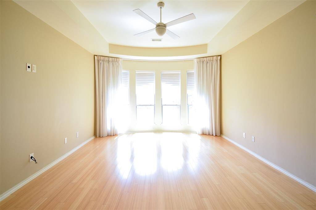 Huge master suite with bay window, Hunter Douglas shades, custom drapes, and wood flooring