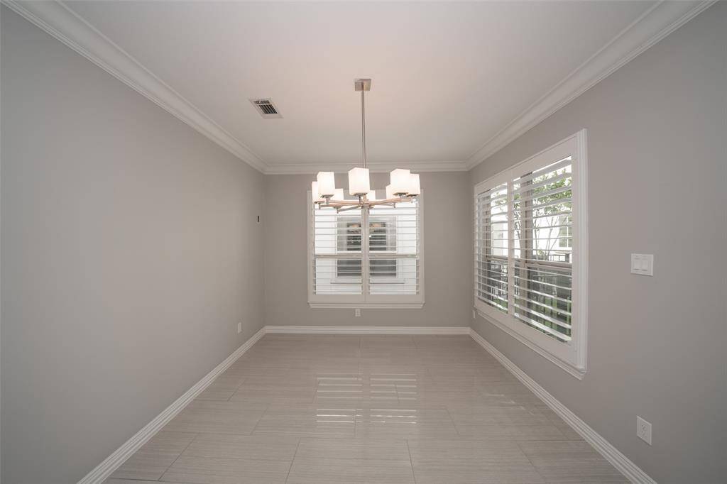 Modern dining room with light gray walls and tiled floors.