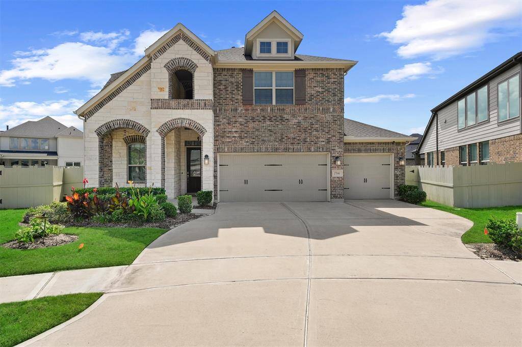 This charming two-story home features a brick and stone exterior, a three-car garage, and a well-maintained front yard with lush landscaping. The arched entryway adds an elegant touch, while large windows provide ample natural light. Ideal for families seeking a spacious and inviting property.