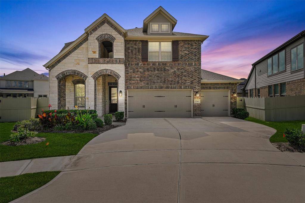 This charming two-story home features a brick and stone exterior, a three-car garage, and a well-maintained front yard with lush landscaping. The arched entryway adds an elegant touch, while large windows provide ample natural light. Ideal for families seeking a spacious and inviting property.