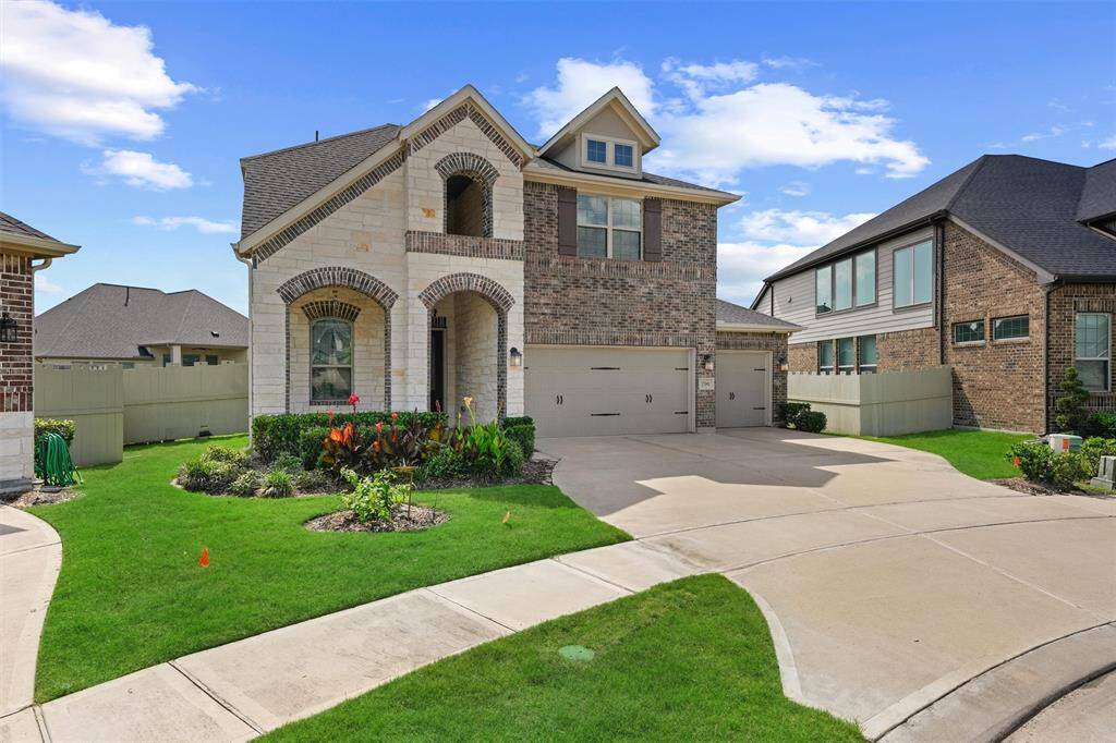 This charming two-story home features a brick and stone exterior, a three-car garage, and a well-maintained front yard with lush landscaping. The arched entryway adds an elegant touch, while large windows provide ample natural light. Ideal for families seeking a spacious and inviting property.