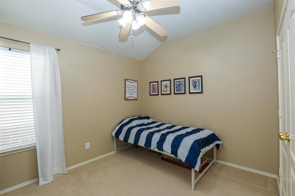 One of 3 secondary bedrooms has neutral paint and a ceiling fan.