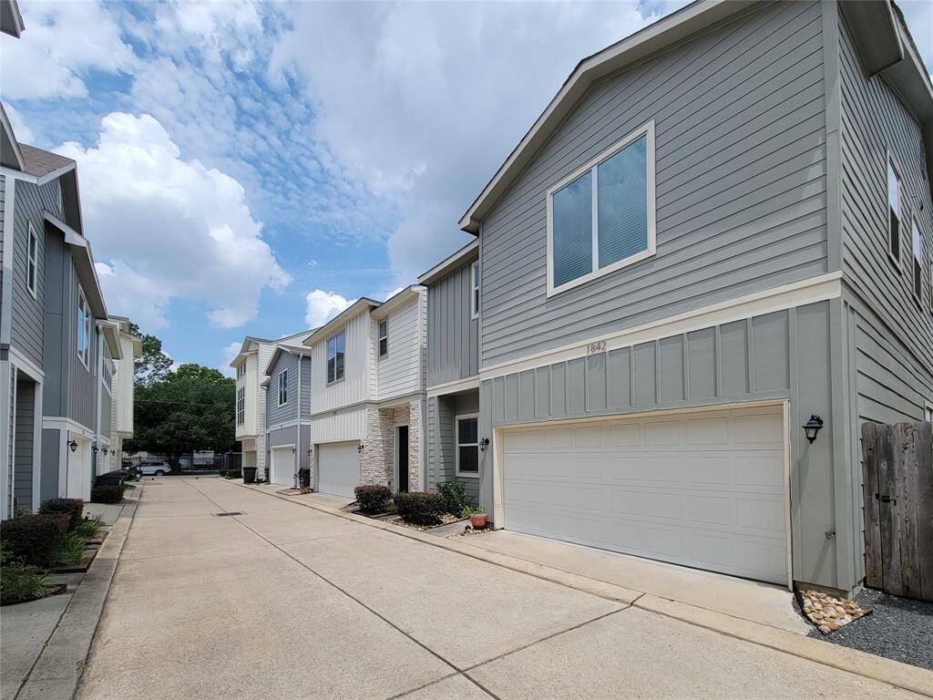 Row of two-story suburban townhouses with a concrete driveway.
