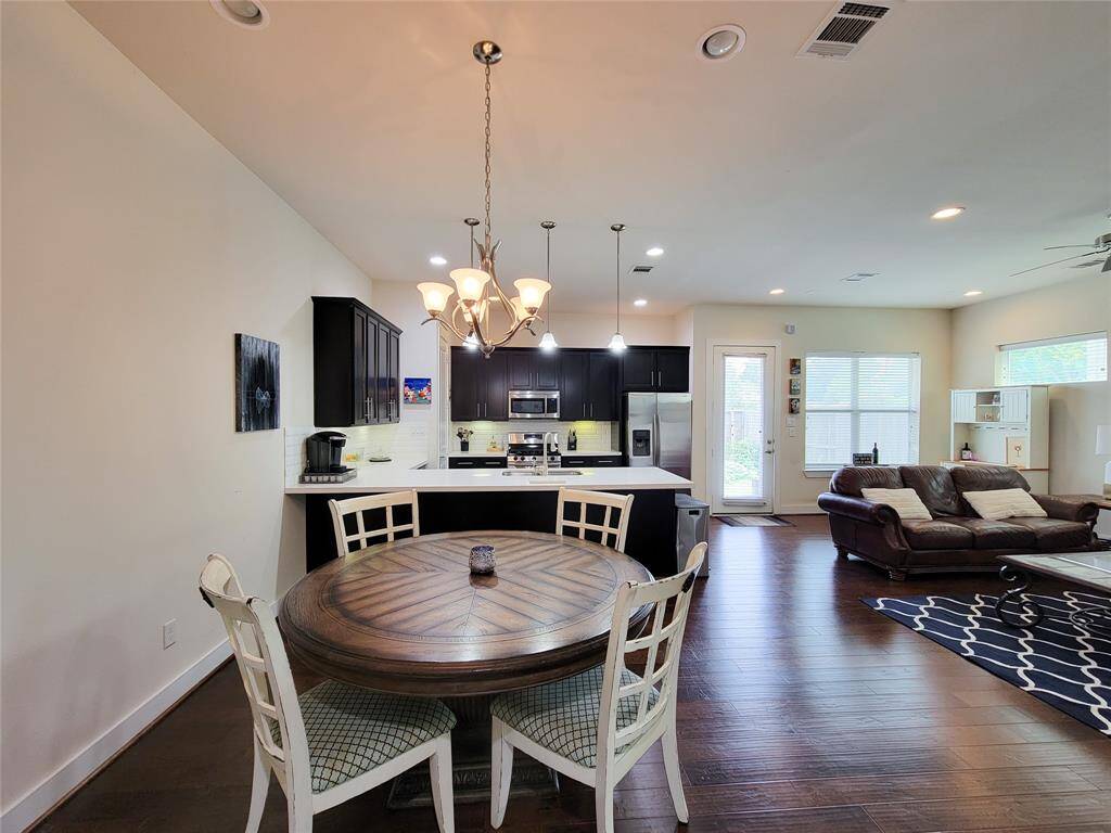 Open-concept living space featuring a kitchen with dark cabinets, dining area, and living room.