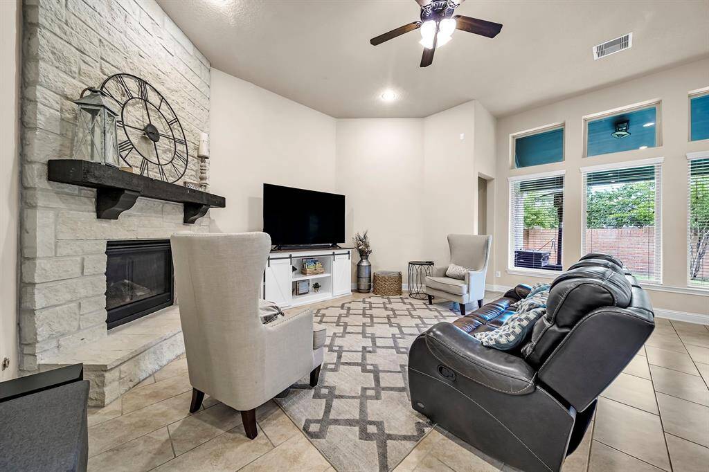 The family room features a floor to ceiling stone fireplace and a wall of windows overlooking the backyard