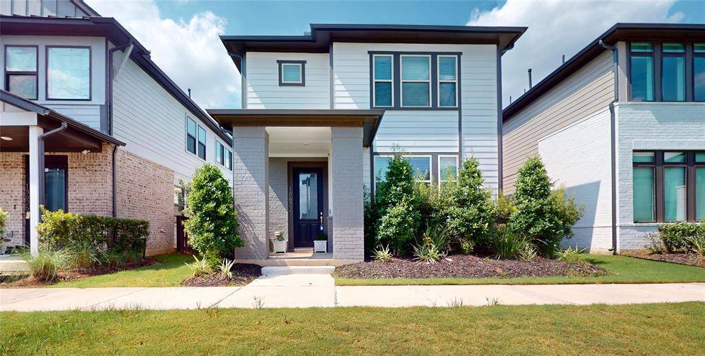 Modern two-story home with sleek lines and a welcoming entrance, surrounded by lush landscaping.
