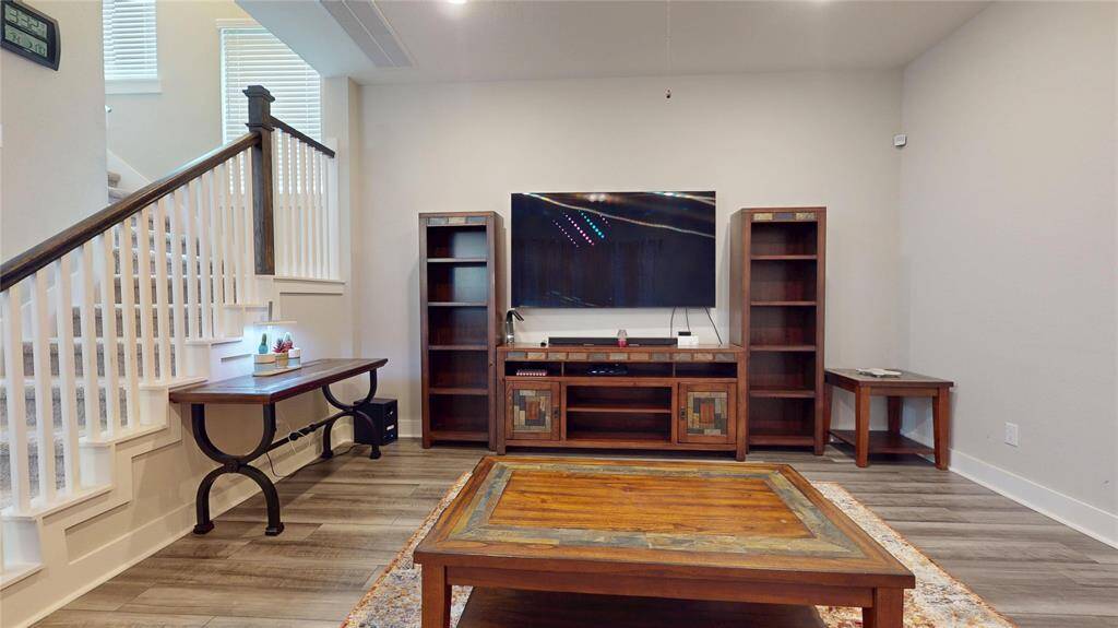 Spacious living area featuring elegant wood flooring, a cozy media setup, and stylish built-in shelving, perfect for relaxation and entertainment.
