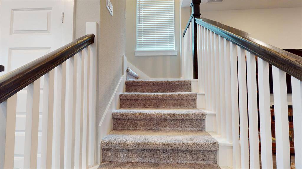 Elegant staircase leading to the second floor, featuring a cozy carpeted finish and classic railing design.