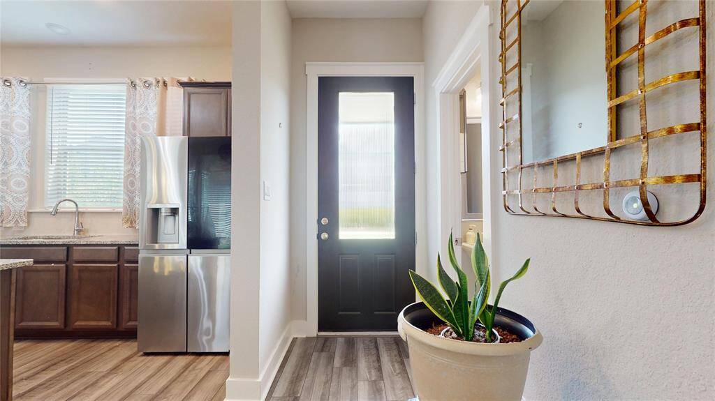 Step into an inviting entryway featuring elegant flooring, a stylish mirror, and abundant natural light, seamlessly connecting to the modern kitchen.