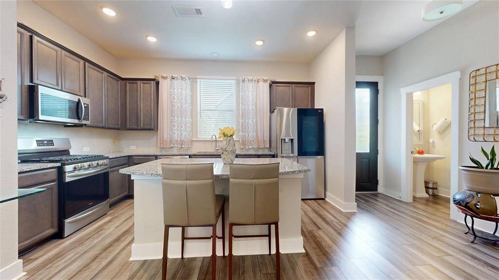 Modern kitchen view from the living area, featuring sleek appliances, stylish cabinetry, and a welcoming island with seating.