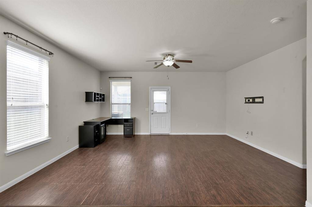 This open-concept living area features a blend of wood and tile flooring, ceiling fans, and a spacious kitchen with ample cabinetry and modern appliances, ideal for entertaining and family gatherings.