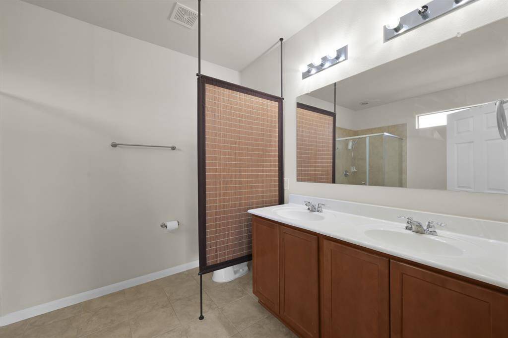 Spacious walk-in closet with ample hanging space and built-in shelving, perfect for organized storage. The room features neutral walls and dark wood flooring.