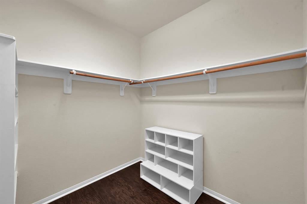 This room features a single window with blinds, neutral walls, and wood flooring. It's equipped with a wall mount for a TV, making it ideal for a cozy media room or office space.
