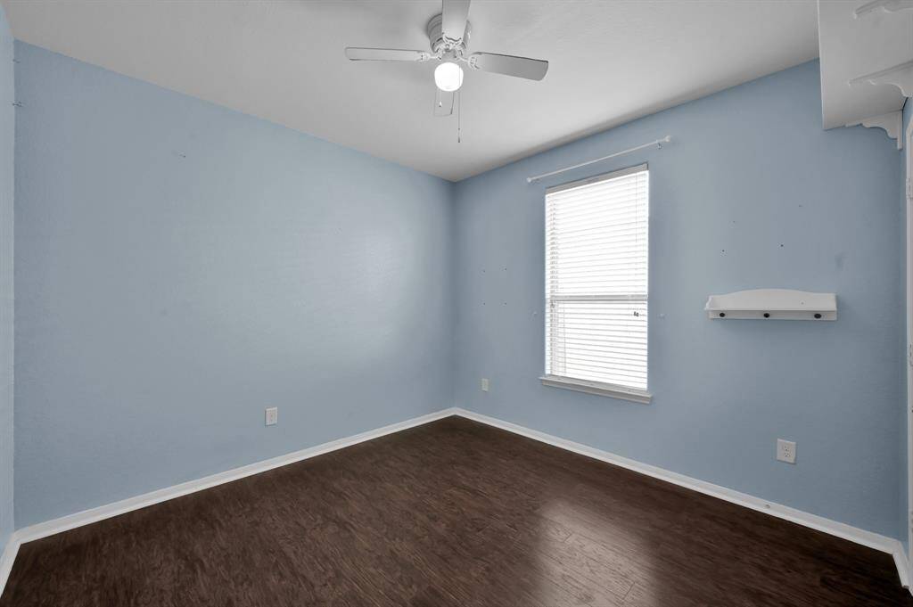 Soothing blue walls, a ceiling fan, and dark wood flooring. It includes a double-door closet with ample storage space above, providing functionality and style.