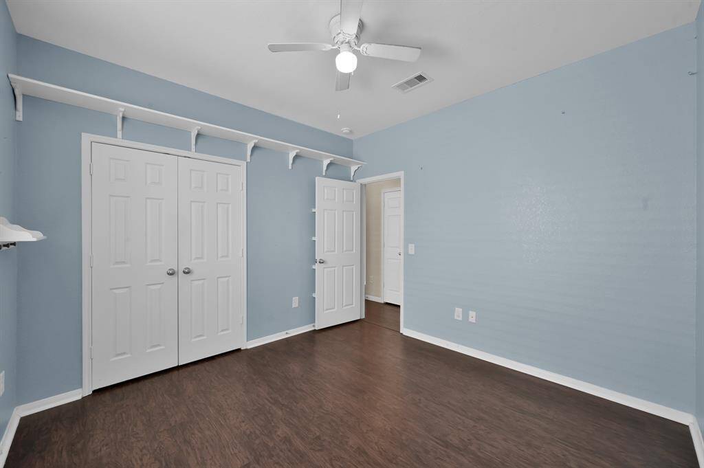 Compact laundry room with a washer and dryer, shelving for storage, and a door leading out. The room has tiled floors and neutral color walls.