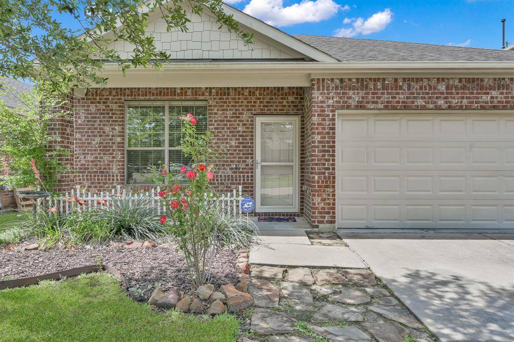 Welcoming front garden and a neatly paved walkway. The front features a large window, a cozy porch area, and a spacious garage. Perfect for those seeking a well-maintained, inviting exterior.