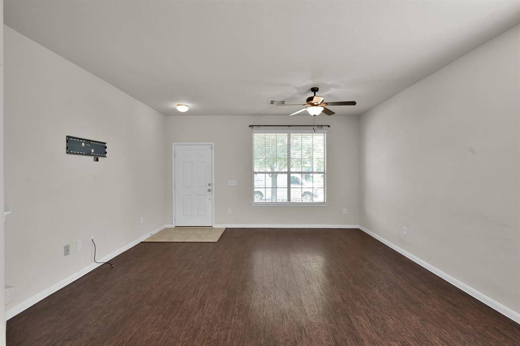 Hardwood flooring, neutral walls, a large window for natural light, and a ceiling fan. T