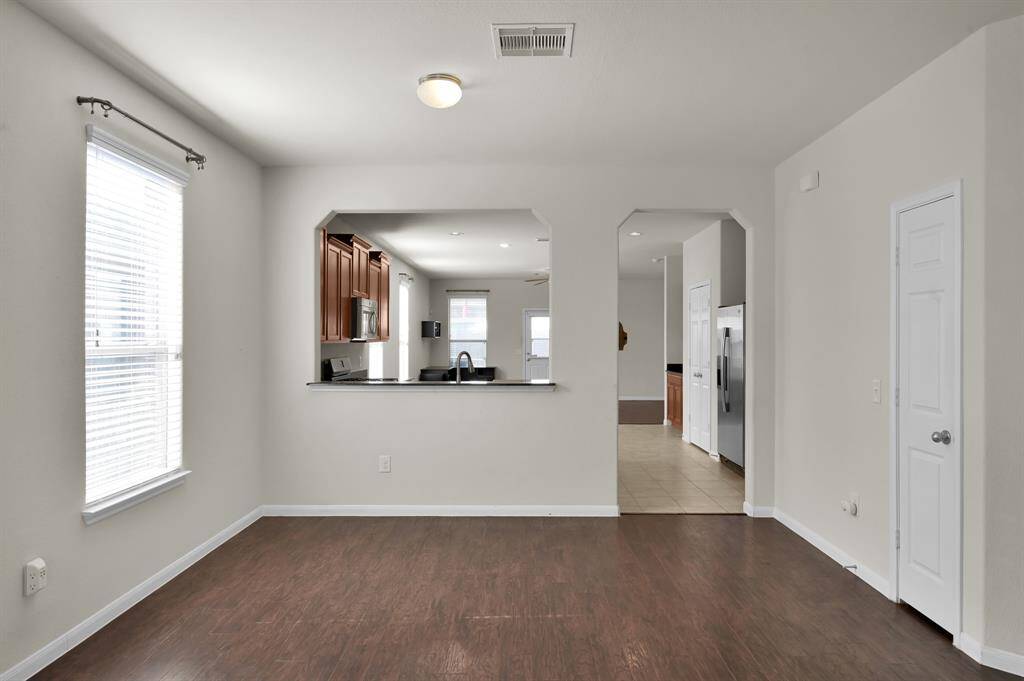 Bright, open-concept kitchen and dining area with hardwood floors and ample natural light. The kitchen features stainless steel appliances and dark wood cabinetry, offering a modern and inviting space for cooking and entertaining.