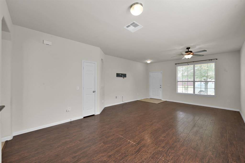 The kitchen features modern appliances, wooden cabinetry, and a central island. The adjoining living space has ample natural light, tile flooring in the kitchen, and wood flooring in the living area, creating a warm and inviting atmosphere.