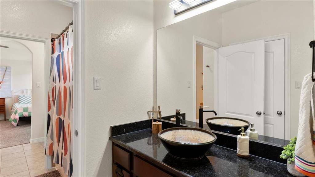 The other side of the Jack-and-Jill bathroom showcases sleek black granite countertops paired with a stylish vessel sink.