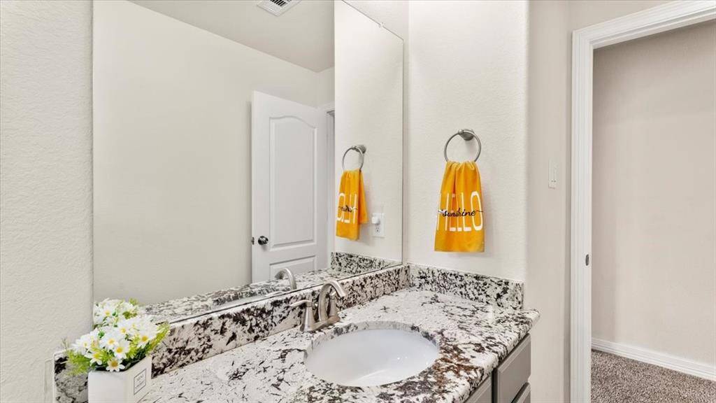 This bathroom features a modern design highlighted by expansive granite countertops, offering a sleek and contemporary aesthetic.