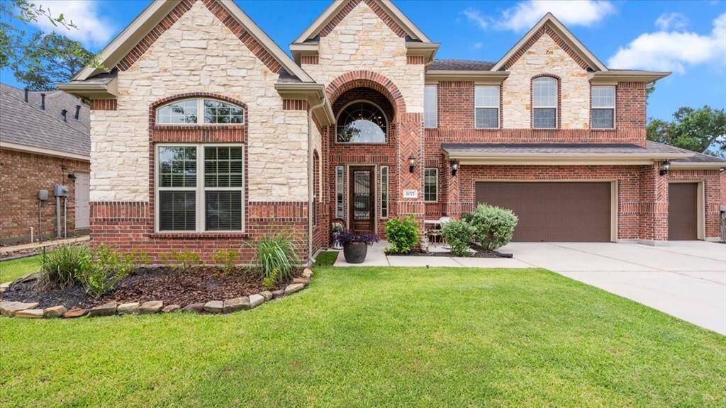 This stunning two-story home showcases a sophisticated blend of brick and stone, complemented by a spacious three-car garage and a meticulously maintained front lawn with manicured landscaping. An elegant arched entryway enhances the curb appeal, while large windows invite an abundance of natural light throughout the home.