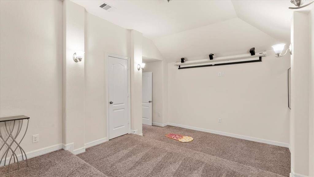 This cozy home theater features tiered carpeted flooring, wall sconces that provide ambient lighting, and a ceiling-mounted projector—creating an inviting and immersive space for entertainment.