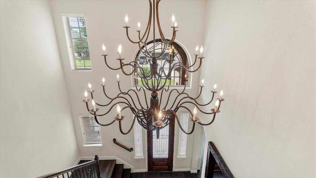 The elegant entryway features a grand chandelier, soaring ceilings, and large windows that flood the space with natural light.