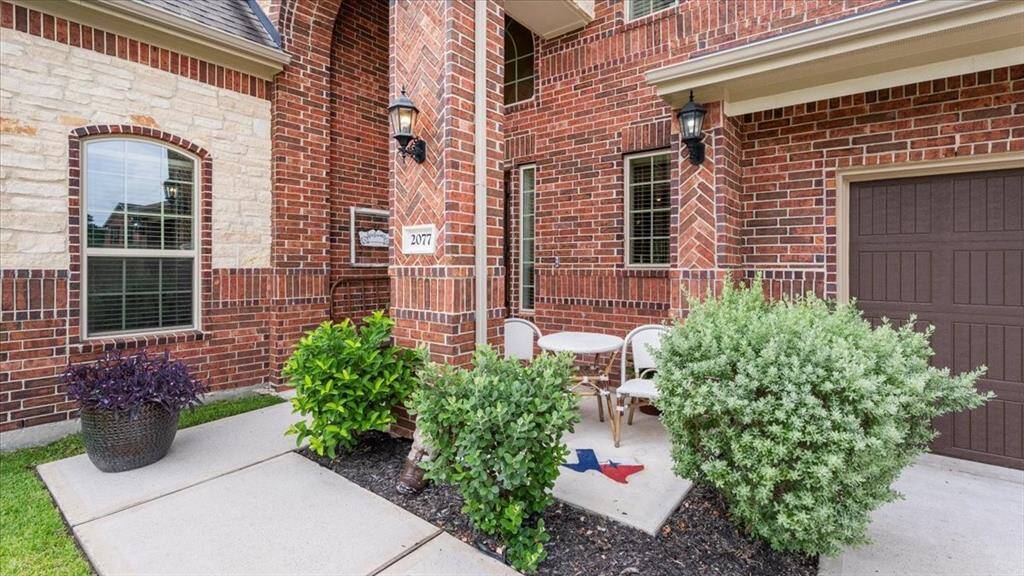 This inviting home features a charming brick exterior with a cozy front patio, perfect for relaxing. It has a well-maintained garden, arched windows, and stylish lighting, adding to its curb appeal.