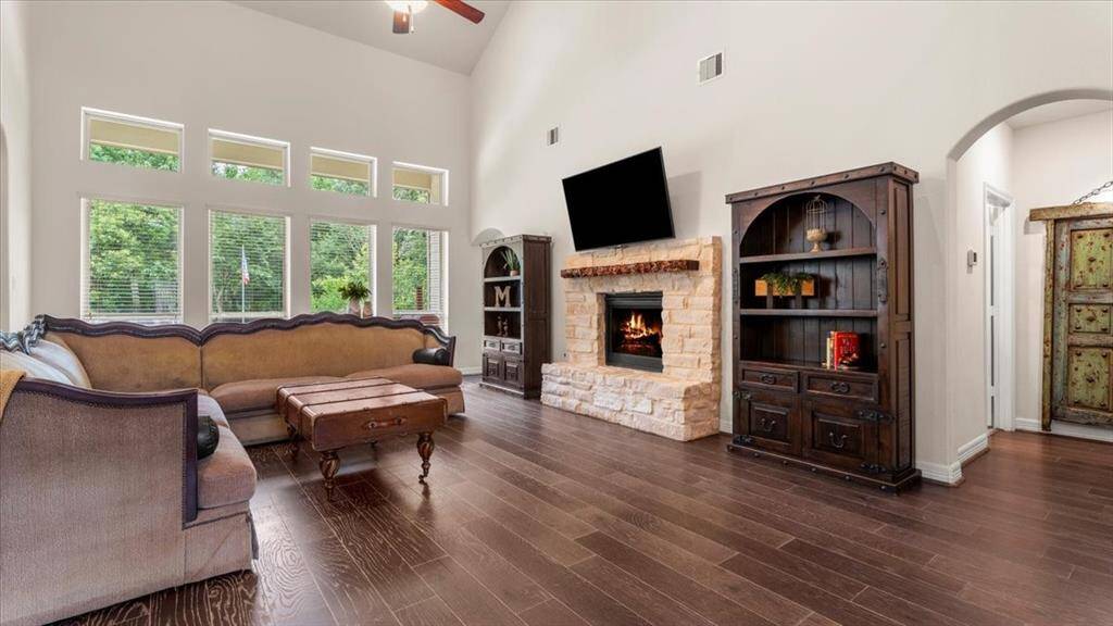 The spacious living room boasts high ceilings and large windows that flood the space with natural light. A cozy stone fireplace and elegant hardwood floors create a warm and inviting atmosphere. The open-concept design seamlessly connects the living room to the kitchen, making it perfect for both relaxation and entertaining.