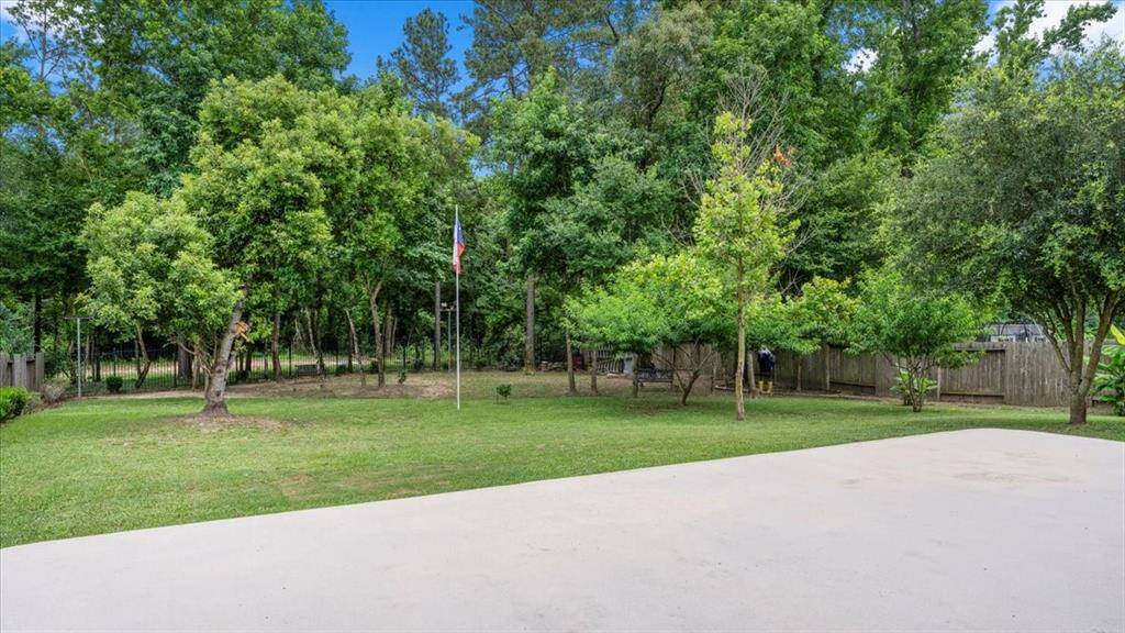 The spacious backyard featuring a lush green lawn, mature trees, and a flagpole, all set against a backdrop of dense woods. With unobstructed views of the greenbelt, this private and serene outdoor space offers a peaceful retreat.