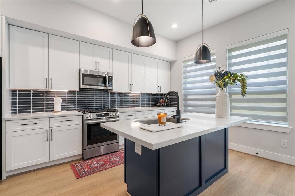 Beautiful kitchen with abundance of cabinets and blue tile backsplash. Quartz countertops and spacious island.