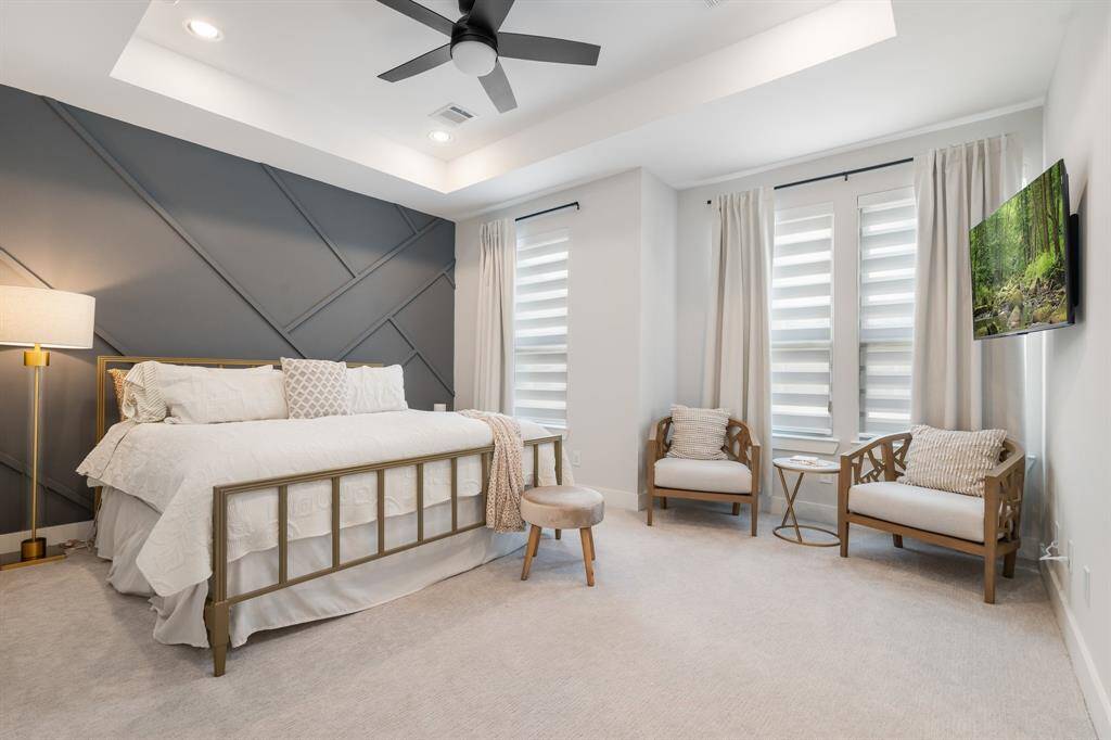Primary bedroom has lots of windows, a tray ceiling and an accent wall too.