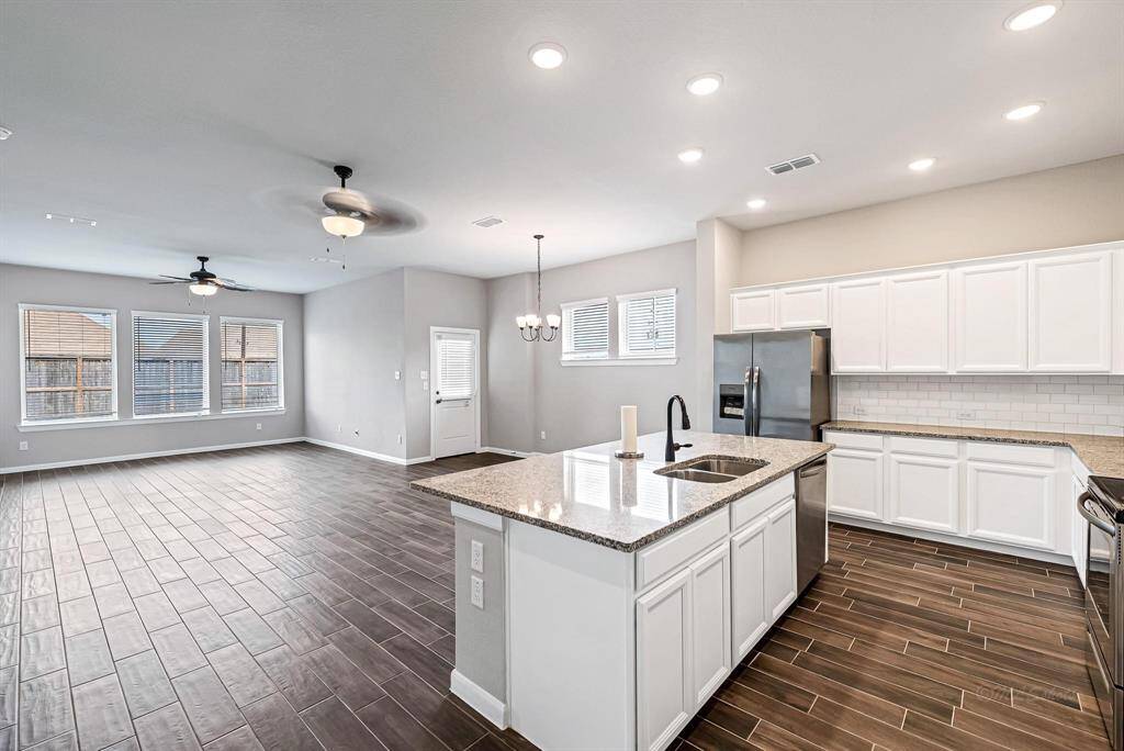 Throughout the home, there is no carpet, only the same wood-like tile flooring, creating a cohesive and easy-to-maintain aesthetic. Additionally, take note of the two fans in the living room, providing both style and comfort.