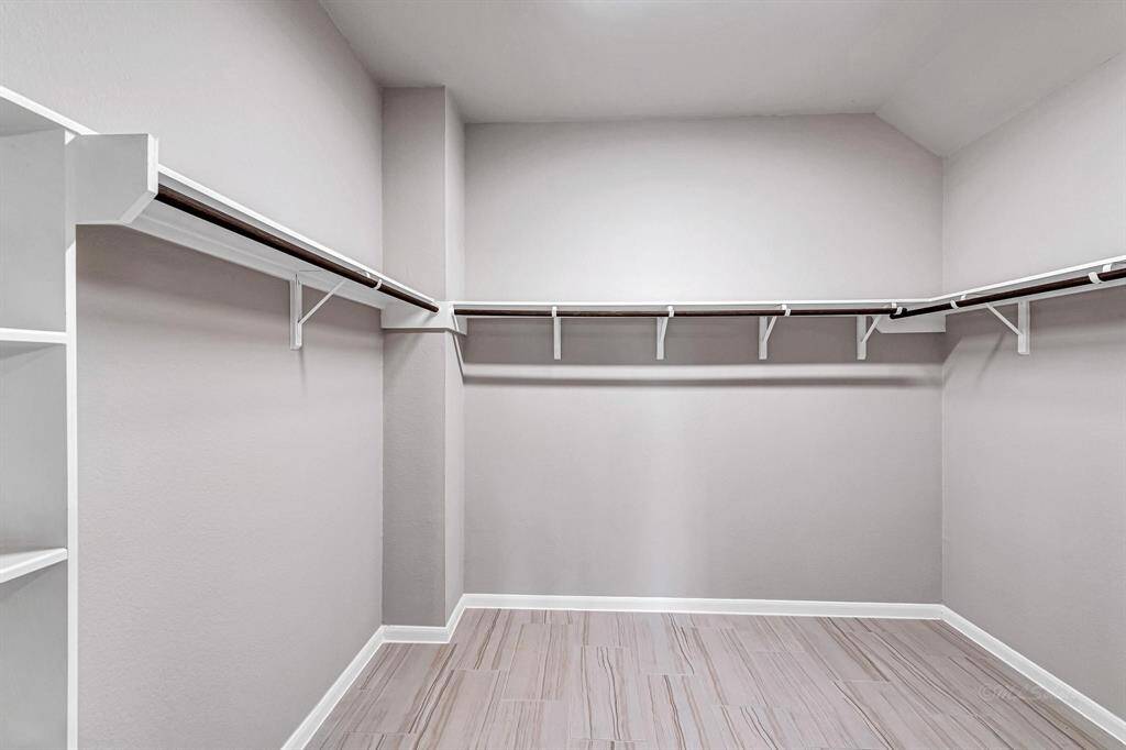 The massive walk-in wardrobe closet is complete with hanging rods throughout, offering ample space for organizing and storing your belongings.