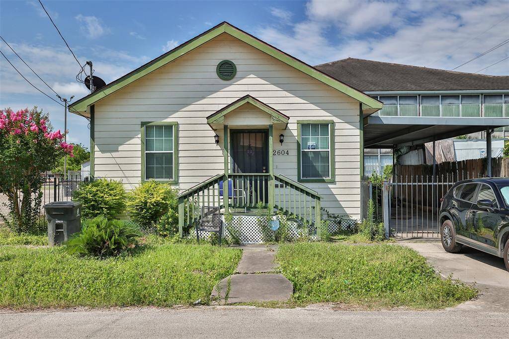 Charming single-story home with a covered front porch and driveway. The exterior features light siding with green trim.